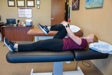 Therapist demonstrating the single knee to chest stretch